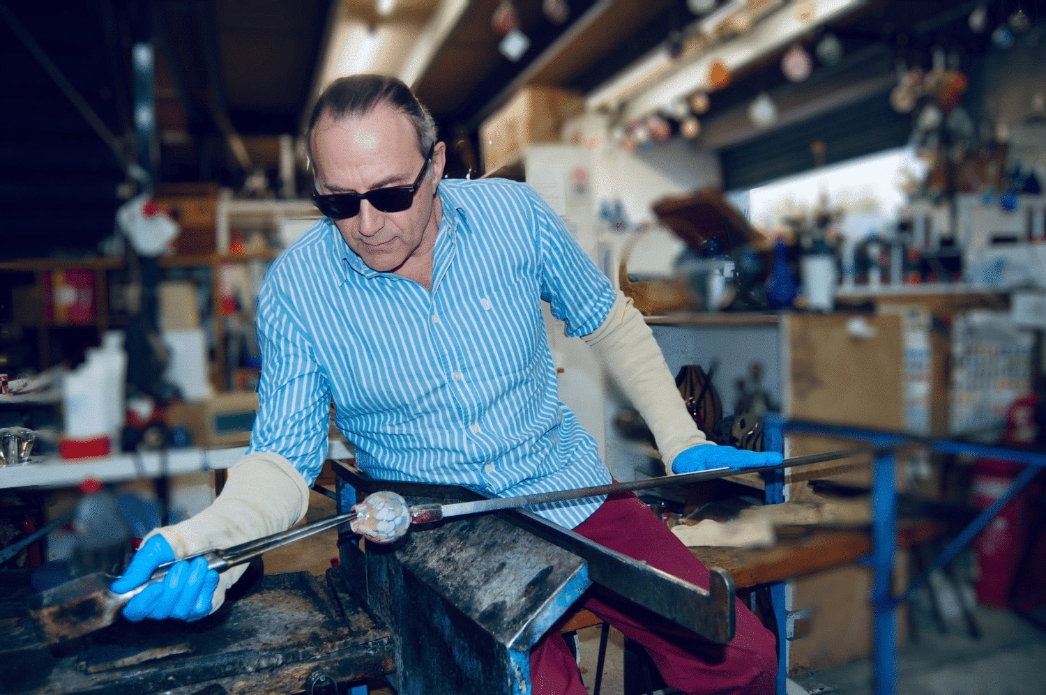 A person in safety gear working with glass in a workshop.